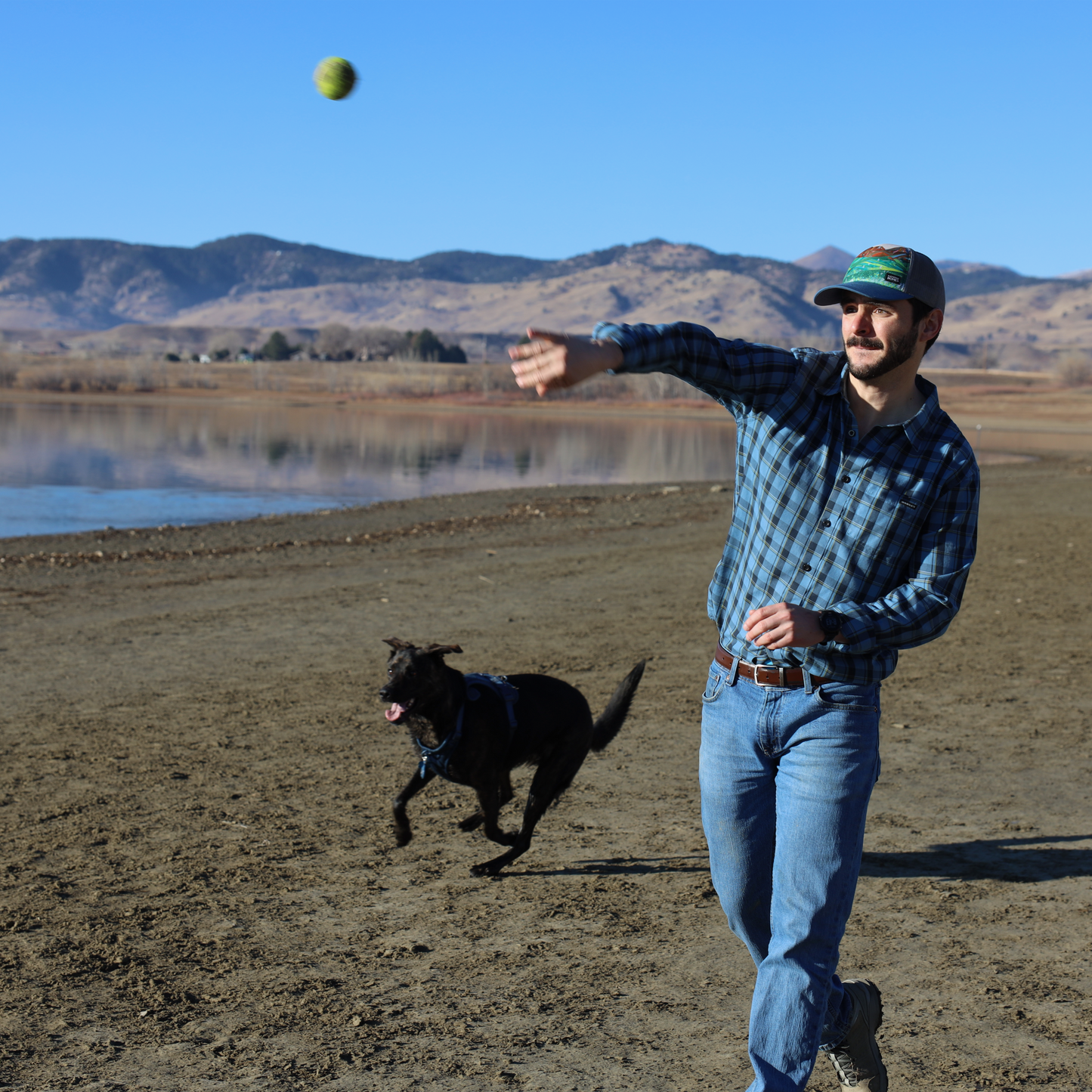 American Basin Mountains Trucker Hat Baseball and Mesh Hat by artist  Katherine Homes worn by man and dog. 
