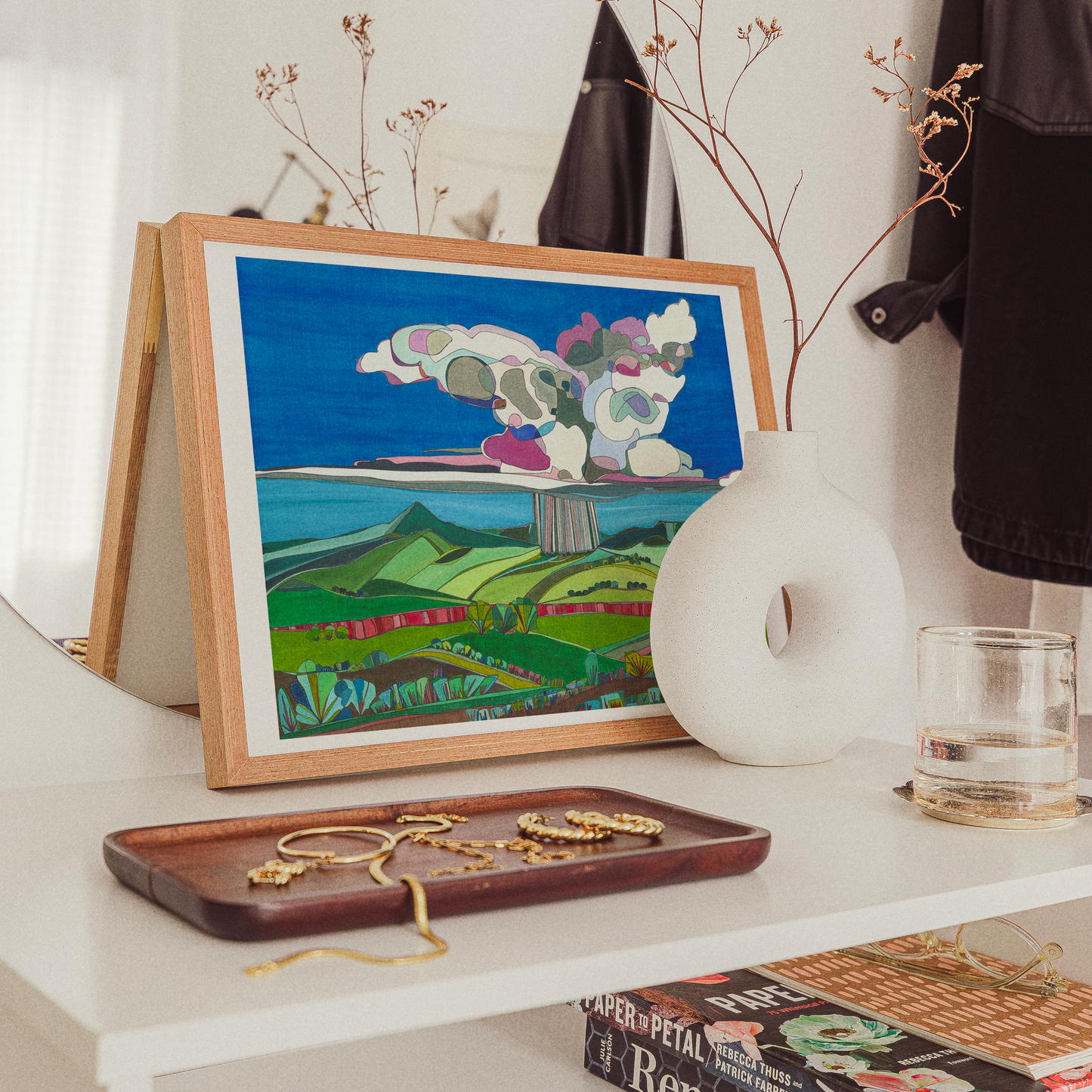 Print of Desert Rain Storm by Katherine Homes on table with books and jewelry 