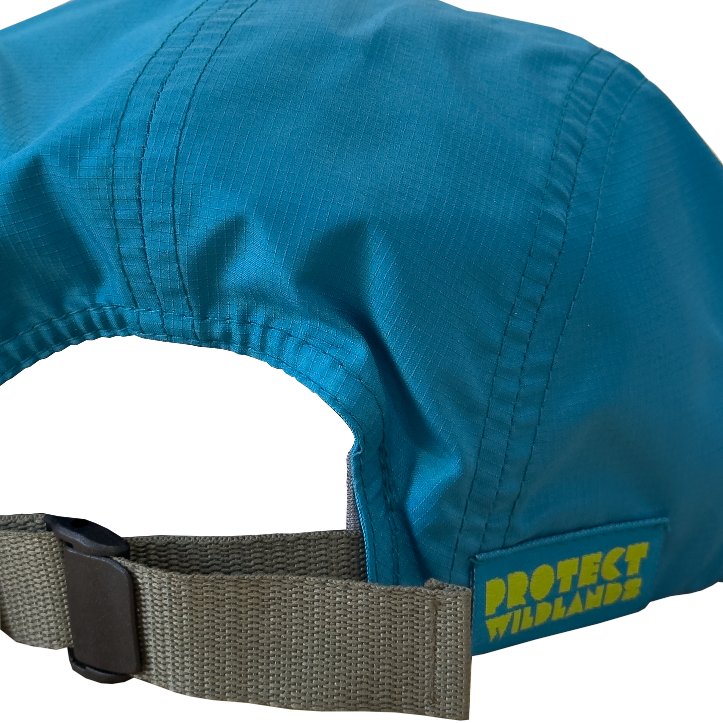 Close-up of the back of a teal blue protective cap with a gray adjustable strap and a yellow 'PROTECT WILDLANDS' logo patch, Katherine Homes, Trio of Summits