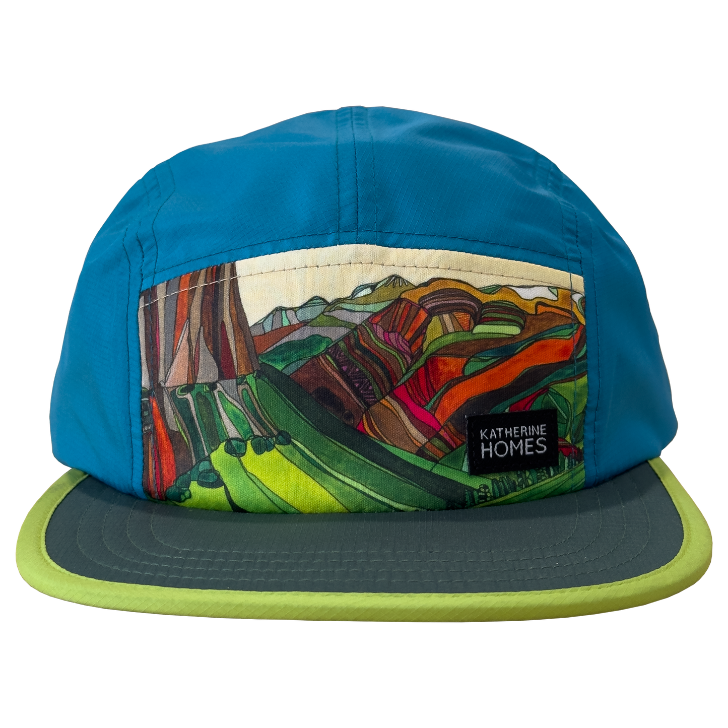 A five-panel cap by Katherine Homes with a bright blue crown, a colorful abstract landscape patch on the front, and a dark gray brim with a lime green edge.