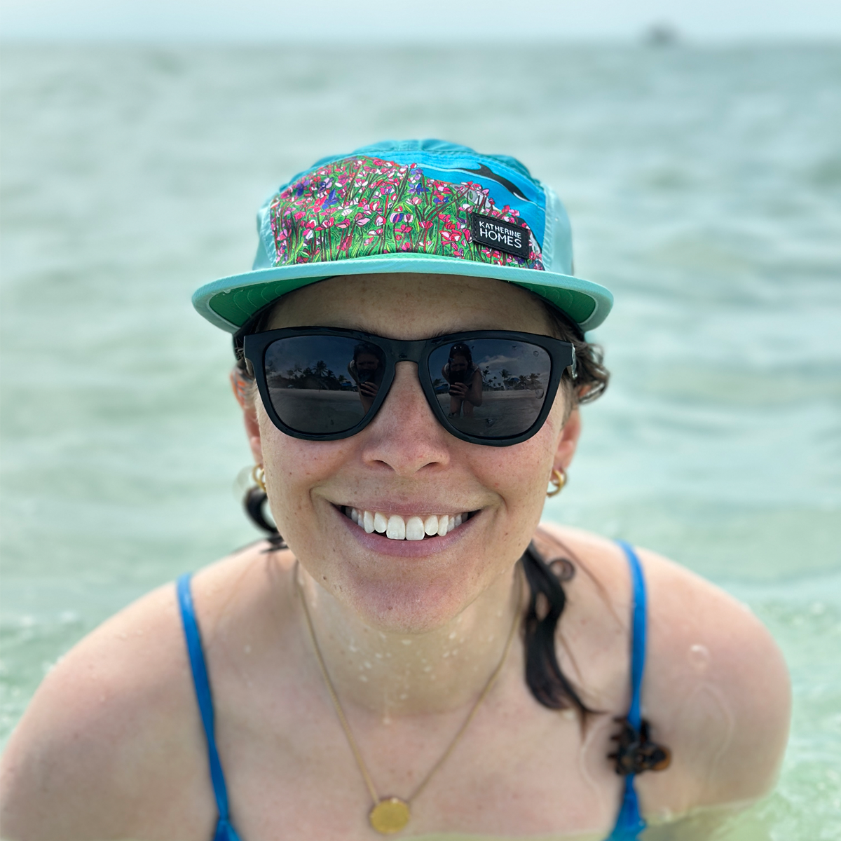 Woman  wearing Travel and  Running Hat, Sun Protection, Wild Orcas, San Juan Islands, Blue and Green,  Baseball Cap adjustable strap by Katherine Homes