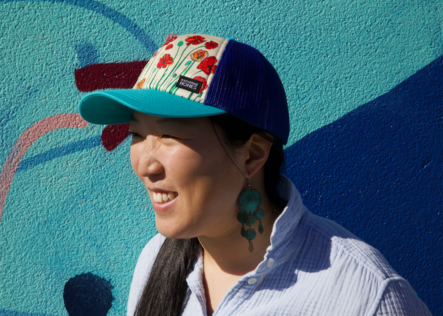 Woman wearing Wild Poppies Royal and Turquoise Trucker Baseball Cap, mesh adjustable  artist  Katherine Homes